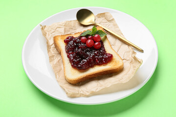 Delicious toast with cranberry jam on plate against color background, closeup