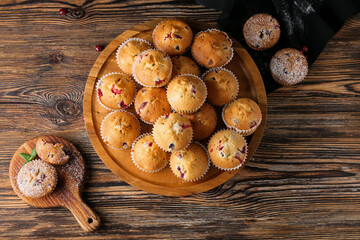 Obraz na płótnie Canvas Stand and board with tasty cranberry muffins on wooden background