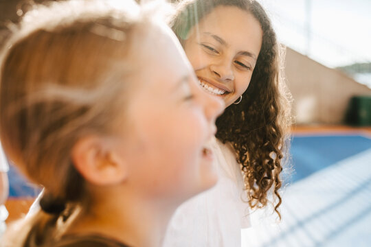 Smiling girl looking at female friend at sports court