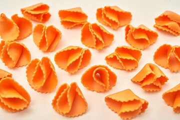 Close-up of small orange curved macaroni with carved edges, childrens food concept