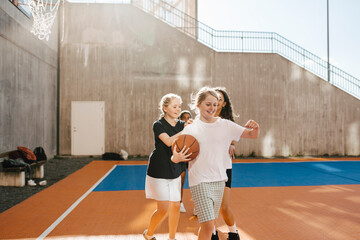 Female friends pulling girl while playing in sports court