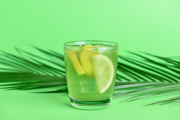 Glass with tasty lemonade on color background