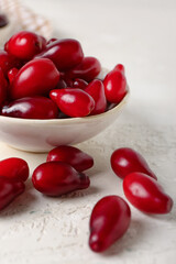 Bowl with ripe dogwood berries on light background, closeup