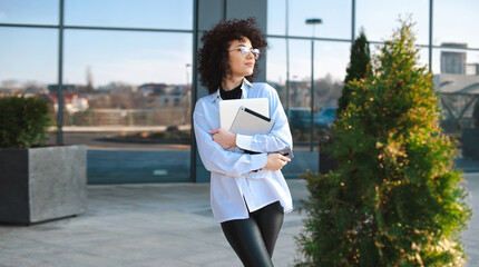 Beautiful portrait of curly hair businesswoman. Stylish woman posing outside with tablet. Business...