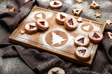 Board with tasty Linzer cookies on dark background