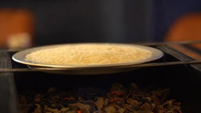 Cooking kunafa on charcoal and fire