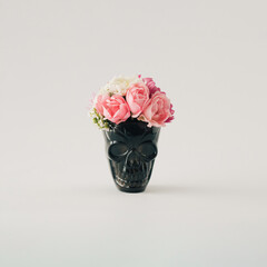 Halloween horror concept with black skull head with colorful autumn flowers. White background. Spooky fun holiday minimal concept.
