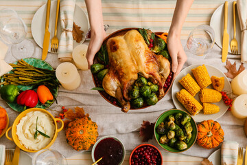 Woman holding plate with delicious roasted turkey above served table