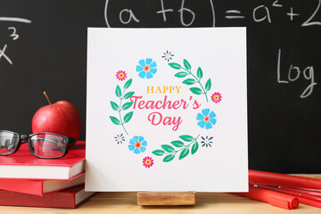 Composition with greeting card on table in classroom. Teacher's Day celebration