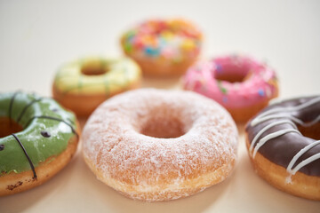 Close-up of sweet glazed donuts with various topping placed in shape of triangle