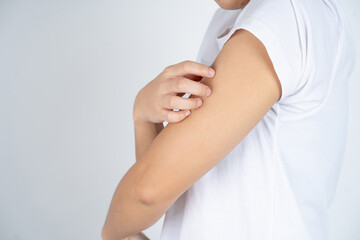 Asian woman scratching arm from having itching. cause of itchy skin include insect bites, dermatitis, or dry skin.