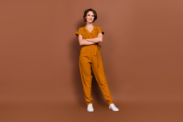 Fototapeta na wymiar Full body photo of positive charming young woman hold hand crossed good mood smile isolated on brown color background