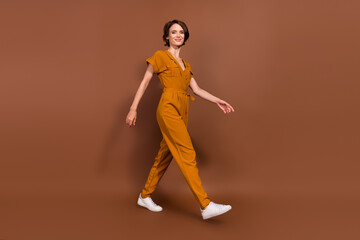 Fototapeta na wymiar Full size photo of cheerful positive young woman walk weekend empty space enjoy isolated on brown color background
