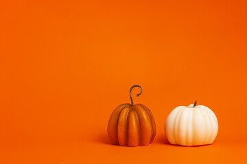 two decorative pumpkin candles on an orange background with copy space. halloween holiday decor, thanksgiving, harvest festival