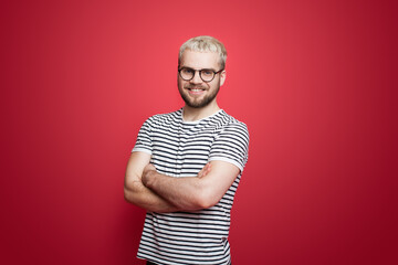 Trendy man with blonde hair posing on red wall with. Handsome man. Smiling man.