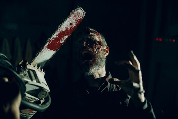 Scary zombie and chainsaw defence halloween party concept. Make up skin and blood on face
