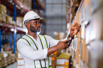 Warehouse worker working process checking the package with a barcode scanner in a large distribution center. an African male supervisor inspects cargo inventory.