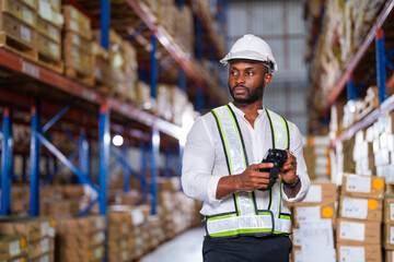 Warehouse worker working process checking the package with a barcode scanner in a large distribution center. an African male supervisor inspects cargo inventory.