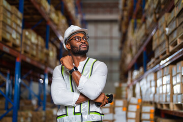Portrait of an African warehouse manager standing in a large distribution center holding barcode...