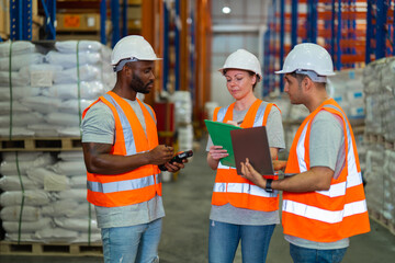 A small group of warehouse workers has a briefing in a large distribution center. concept of teamwork and occupation.
