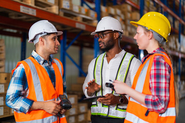 A small group of warehouse workers has a briefing in a large distribution center. concept of teamwork and occupation.