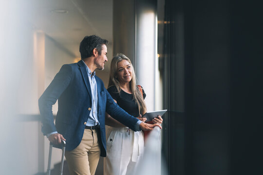Smiling businesswoman and male professional talking in hotel