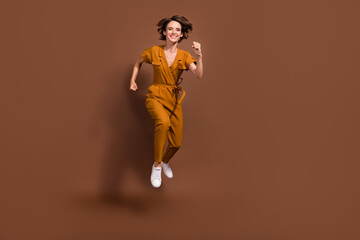Fototapeta na wymiar Full body photo of charming joyful young woman jump up run hurry sale discount isolated on brown color background