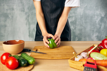 Cook woman on the kitchen cutting vegetables