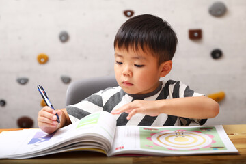 机の上で勉強をする男の子。