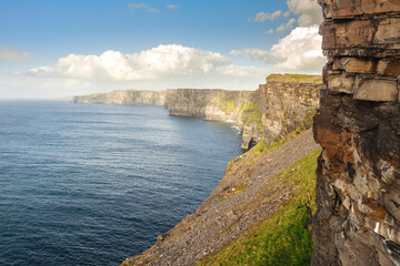Spectacular scenery of Cliff of Moher, county Clare, Ireland. Warm sunny day. cloudy sky. Irish landscape.