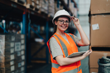 Portrait of a warehouse worker standing in a distribution center. Caucasian female looking at...