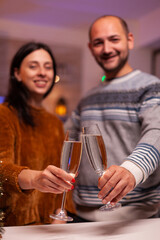 Joyful couple clinking glass of wine celebrating christmas traditional holiday in xmas decorated kitchen. Romantic happy family spending christmastime together enjoying winter season