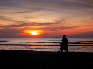 Fototapeta premium Asian male tourists by motorcycle silhouette at sea