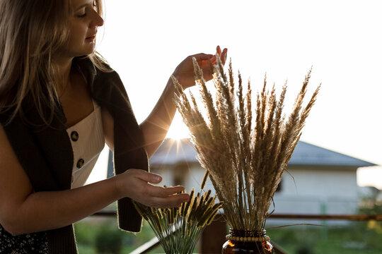 Young woman touching dry grass in flower pot