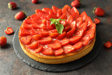 Tray with strawberry tart on dark textured table