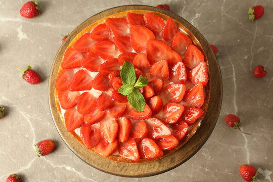 Wooden stand with strawberry tart on gray textured background