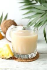 Pina colada cocktail and ingredients on white wooden table
