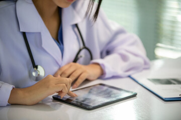 Asian women doctor working and analyzing x-ray images at hospital office