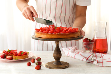 Woman in apron cut the strawberry tart
