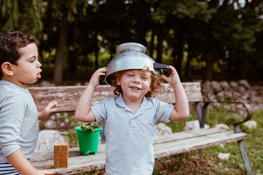 Happy boy wearing colander on head while standing by male friend