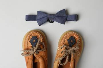 Baby shoes and bow tie on light gray background