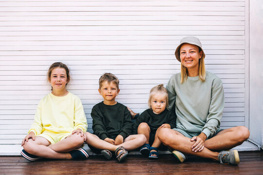Smiling mother with sons and daughter sitting in front of shutter
