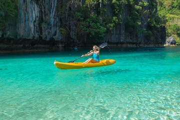 Woman on a kayak in the Small Lagoon with azure water, El Nido, Palawan, Philippines.