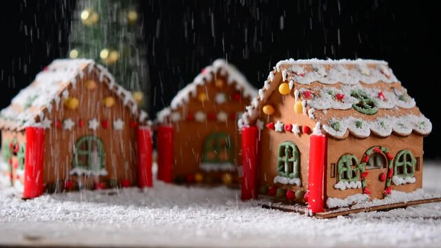 Falling snow on gingerbread house on black background