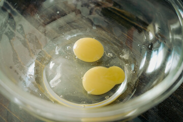 Blurry photo of a Yellow egg yolks in a clear transparent bowl.