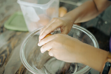 Obraz na płótnie Canvas Closeup of a pair of hands cracking an egg into a glass bowl