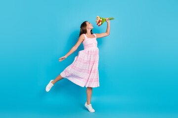 Full size photo of happy joyful young woman hold flowers smell graceful girl isolated on blue color background