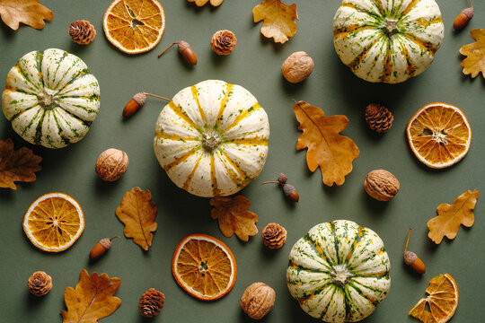 Autumn composition with ripe pumpkins, dry oak leaves, walnuts, acorns on vintage green background. Autumn, fall, harvest concept. Flat lay, top view
