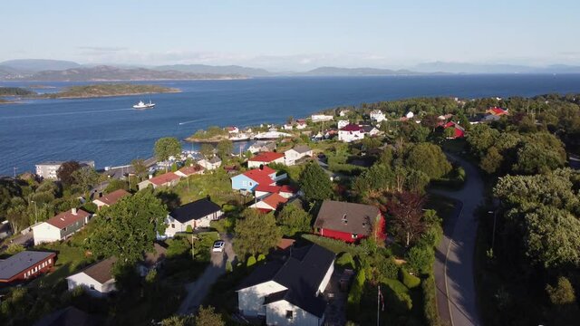 Flying above Sotra island with Leroyosen fjord in background -- Fishing vessel is heading for sea during late afternoon