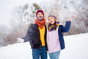 Fototapeta na wymiar Photo of cheerful handsome guy positive attractive lady arm palm catch throw snow toothy smile look camera outdoors